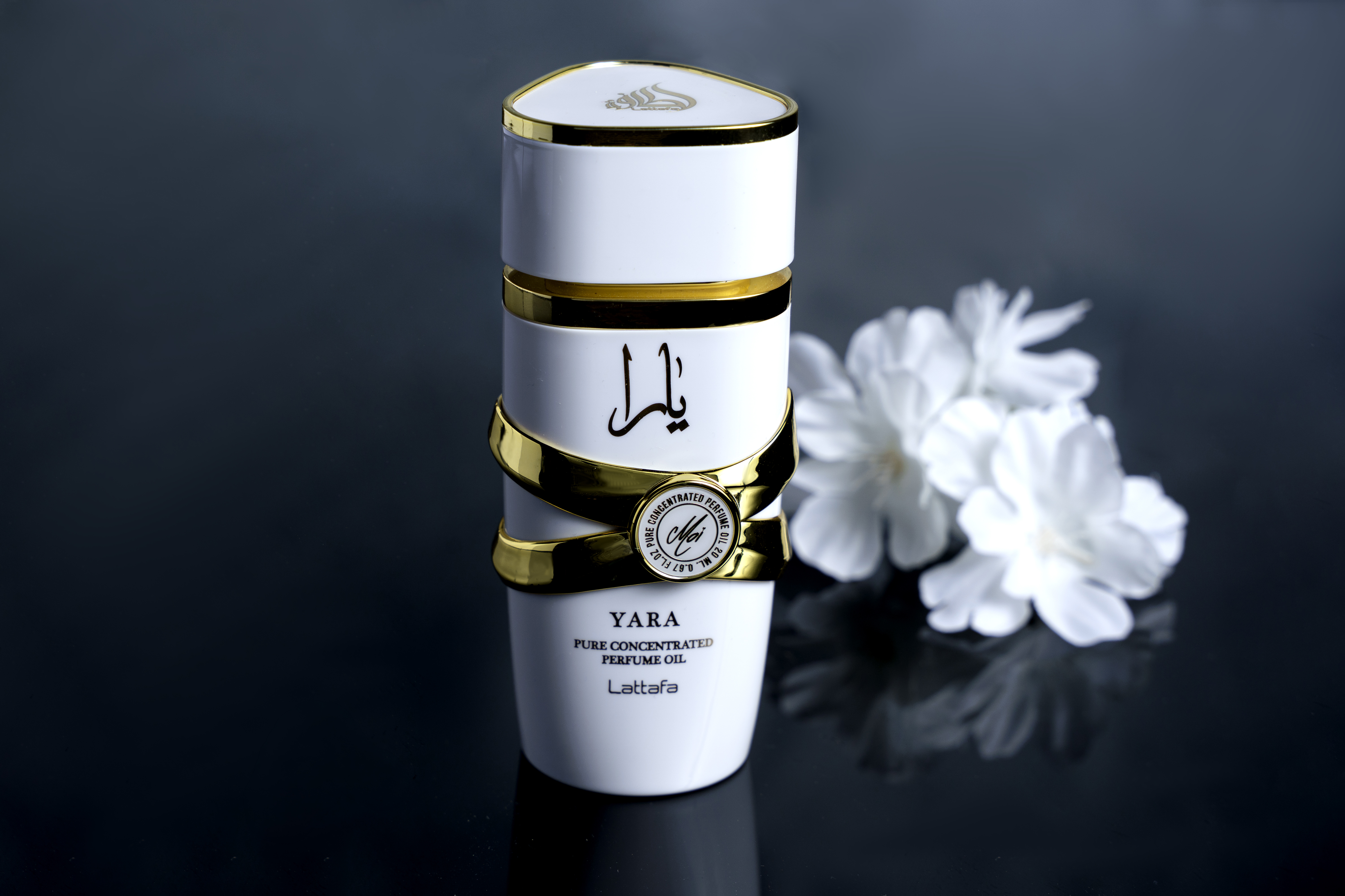 Perfume blanco y dorado junto a flores blancas